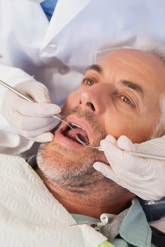 Dentist examining a patients teeth in the dentists chair at the dental practice tepper